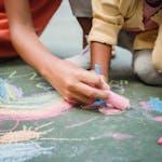 Creative fun with kids using colorful chalks on pavement, perfect for outdoor activities.