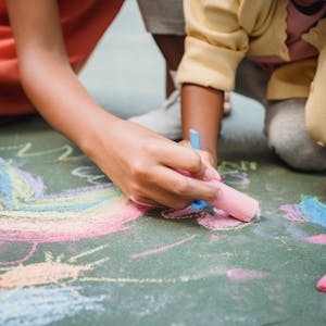Creative fun with kids using colorful chalks on pavement, perfect for outdoor activities.