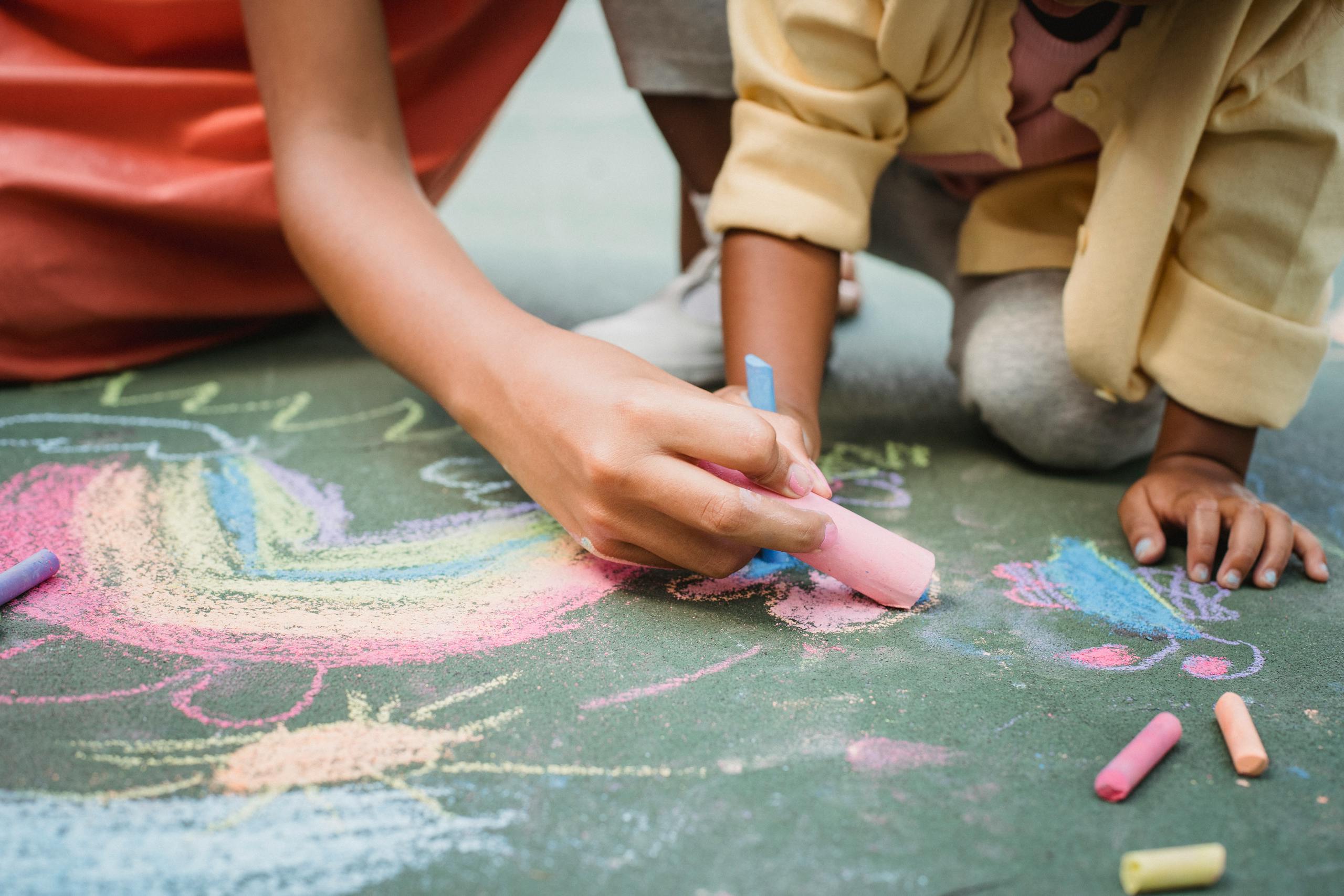 Creative fun with kids using colorful chalks on pavement, perfect for outdoor activities.