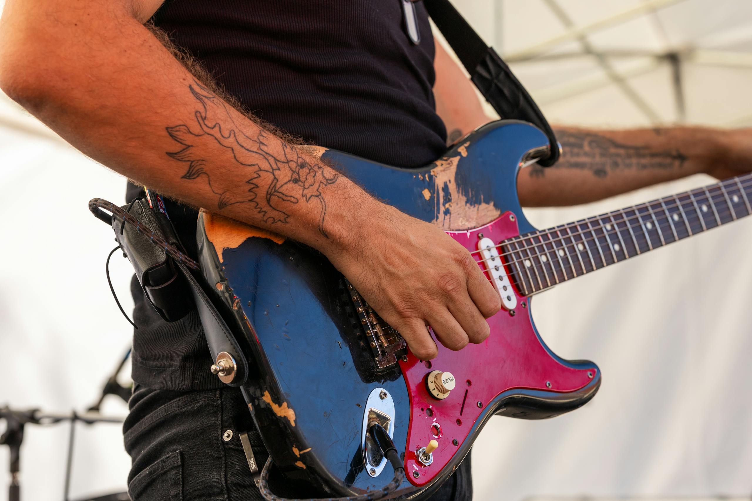 Close-up of a guitarist playing an electric guitar at an outdoor rock concert.